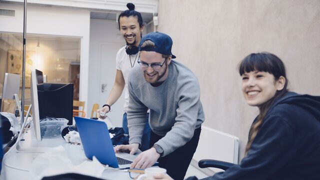 Happy male and female computer programmers at desk in office Small without overlay